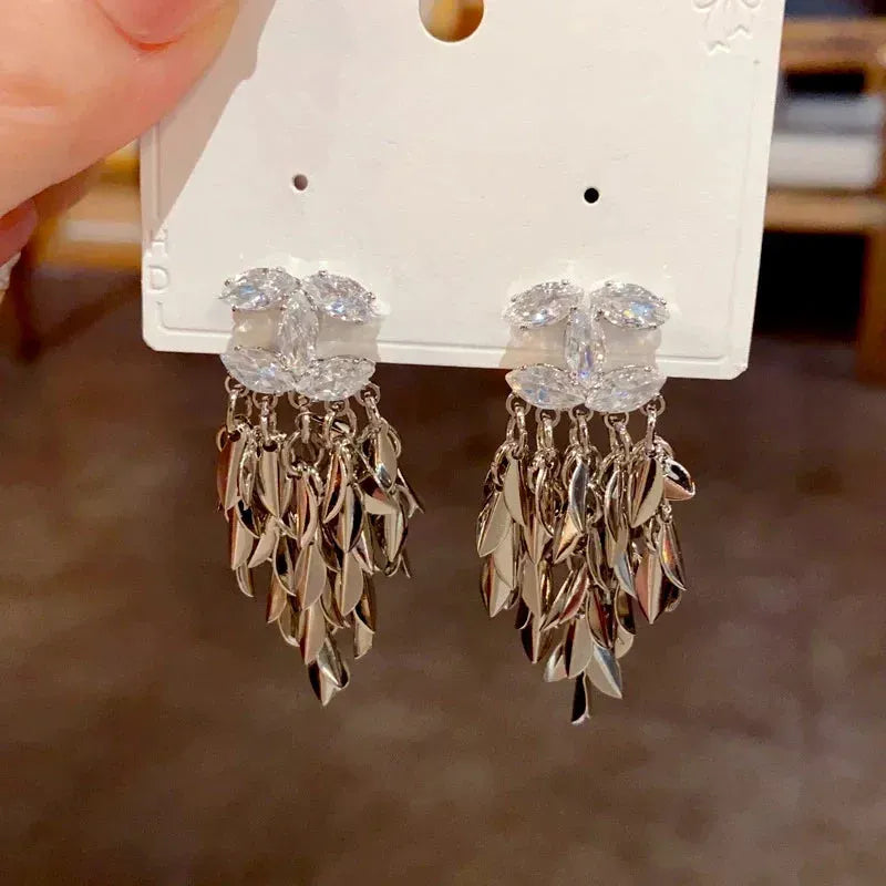 Model showcasing the dangle and style of the 14K Gold-Plated Elegant Zircon Chanel Style Leaf Tassel Earrings