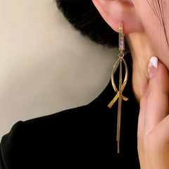 Model showcasing the dangle and style of the 14K Gold-Plated Elegant Zircon Cross Tassel Earrings