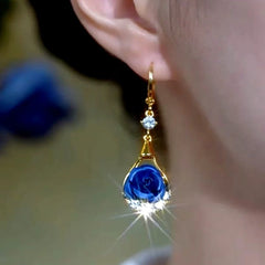 Model showcasing the dangle and style of the 14K Gold-Plated Elegant Zircon Diamond Blue Rose Flower Earrings