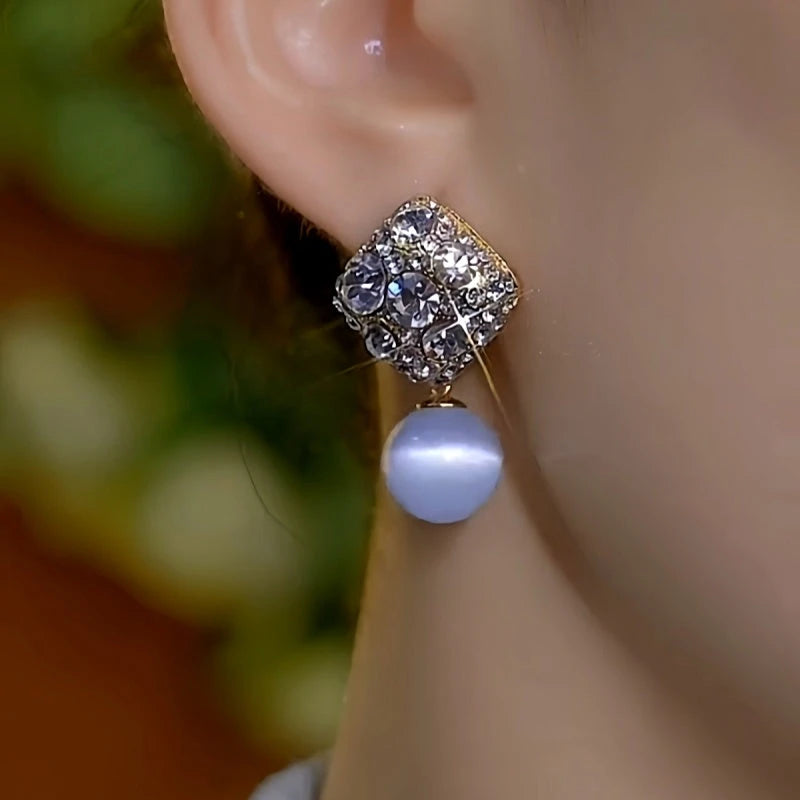 Model showcasing the dangle and style of the 14K Gold-Plated Elegant Zircon Diamond Cat's Eye Bead Earrings