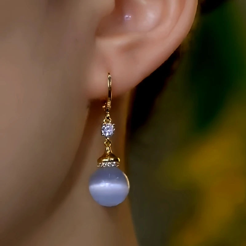 Model showcasing the dangle and style of the 14K Gold-Plated Elegant Zircon Diamond Cat's Eye Stone Bead Earrings