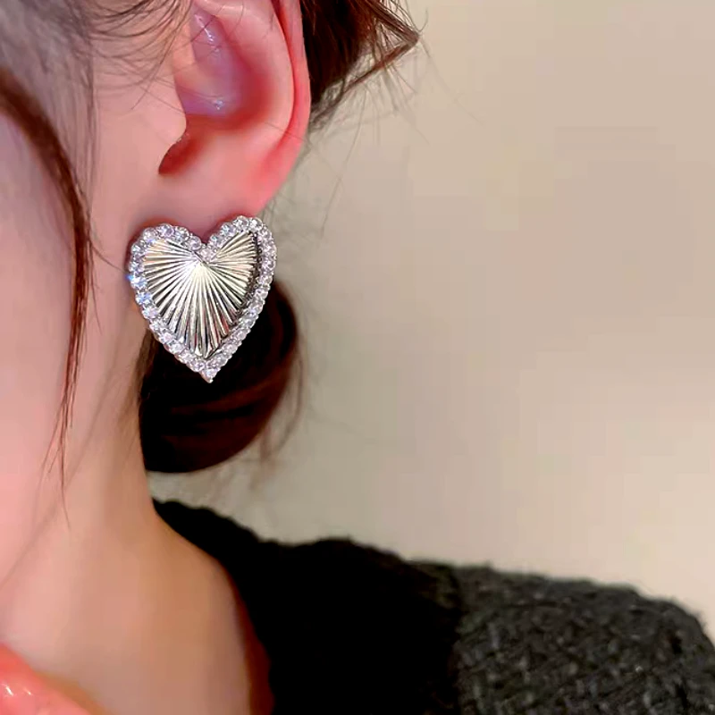 Model showcasing the dangle and style of the 14K Gold-Plated Elegant Zircon Diamond Heart Stud Earrings