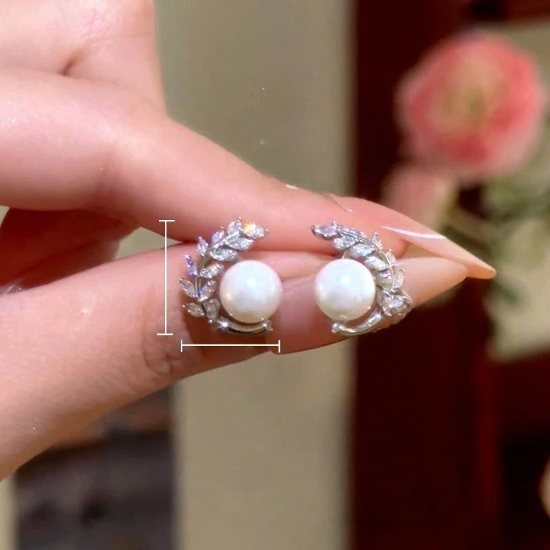 Model showcasing the dangle and style of the 14K Gold-Plated Elegant Zircon Diamond Leaf Pearl Stud Earrings