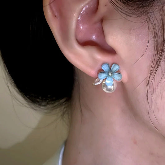Model showcasing the dangle and style of the 14K Gold-Plated Elegant Zircon Diamond Pearl Blue Flower Stud Earrings