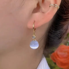 Model showcasing the dangle and style of the 14K Gold-Plated Elegant Zircon Diiamond White Cat's Eye Stone Earrings