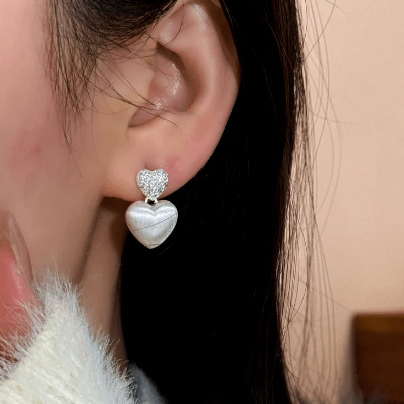 Model showcasing the dangle and style of the 14K Gold-Plated Elegant Zircon Double Heart Earrings