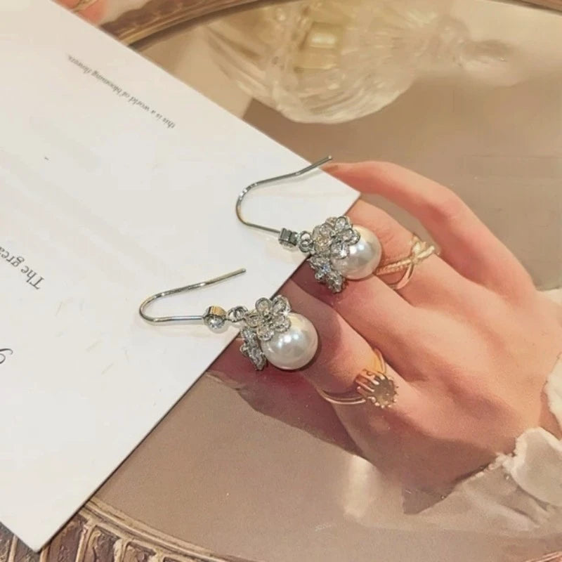 Model showcasing the dangle and style of the 14K Gold-Plated Elegant Zircon Flower Bead Ear Hooks