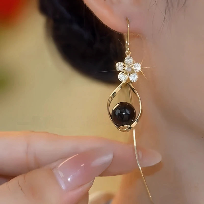 Model showcasing the dangle and style of the 14K Gold-Plated Elegant Zircon Flower Black Bead Threader Earrings