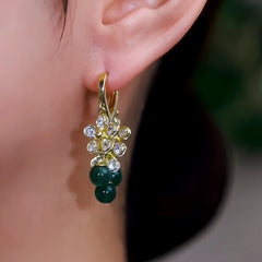 Model showcasing the dangle and style of the 14K Gold-Plated Elegant Zircon Flower Green Bead Tassel Earrings
