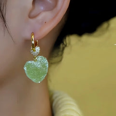 Close-up detail of the sparkling zircons and plating on the green heart earrings