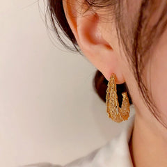 Close-up detail of the sparkling zircons and plating on the gold geometric earrings