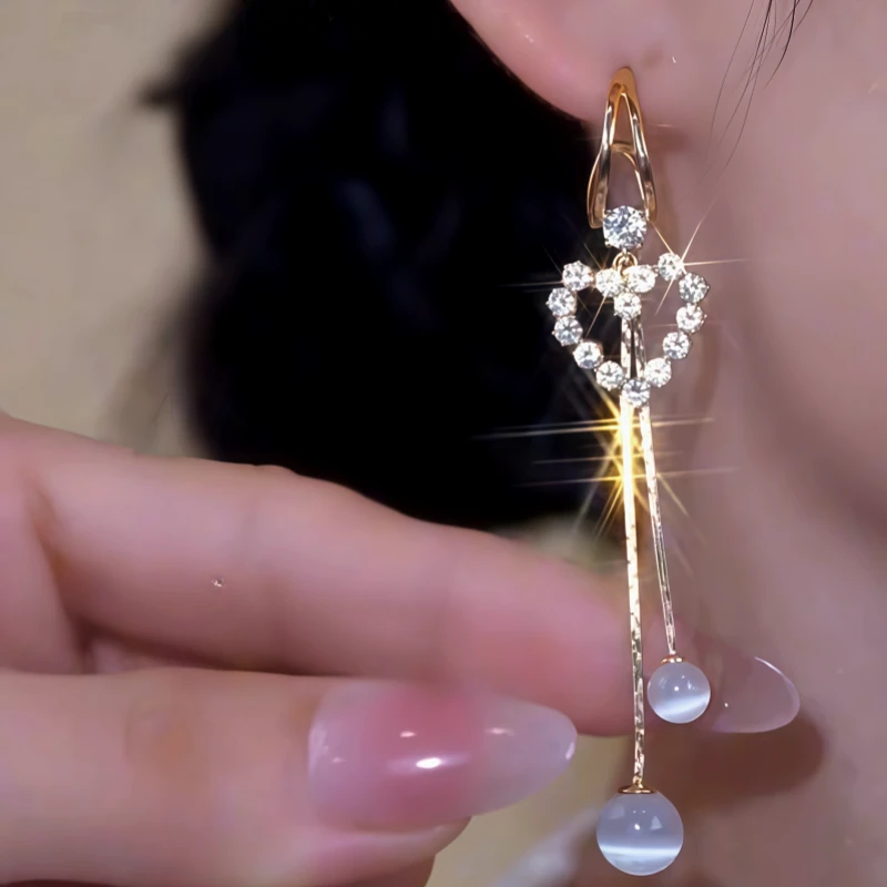 Model showcasing the dangle and style of the 14K Gold-Plated Elegant Zircon Heart Bead Tassel Earrings