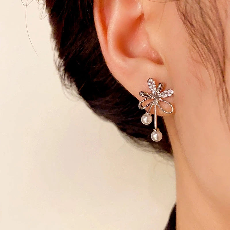 Model showcasing the dangle and style of the 14K Gold-Plated Elegant Zircon Knotted Pearl Earrings