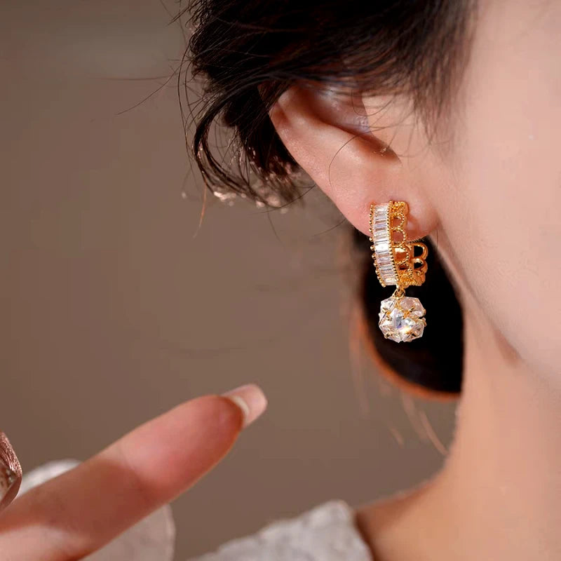 Close-up detail of the sparkling zircons and plating on the gold drop earrings