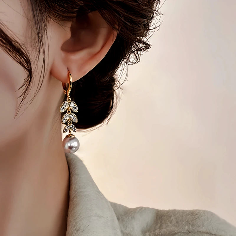 Model showcasing the dangle and style of the 14K Gold-Plated Elegant Zircon Leaf Pearl Tassel Earrings