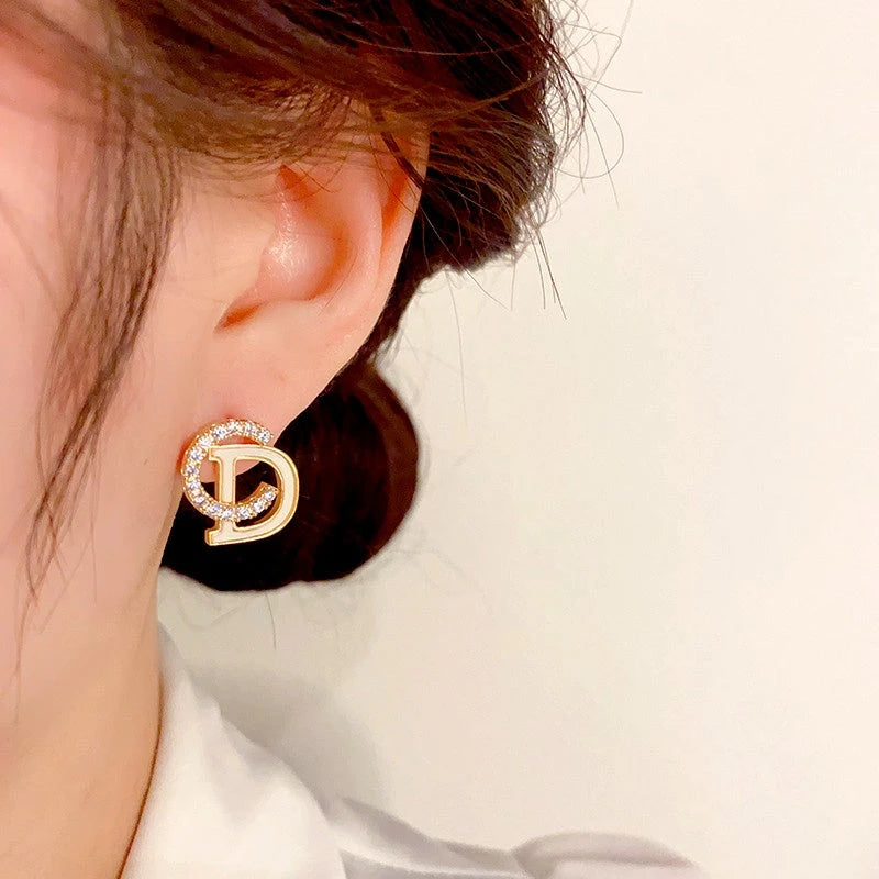 Model showcasing the dangle and style of the 14K Gold-Plated Elegant Zircon Letter CD Stud Earrings