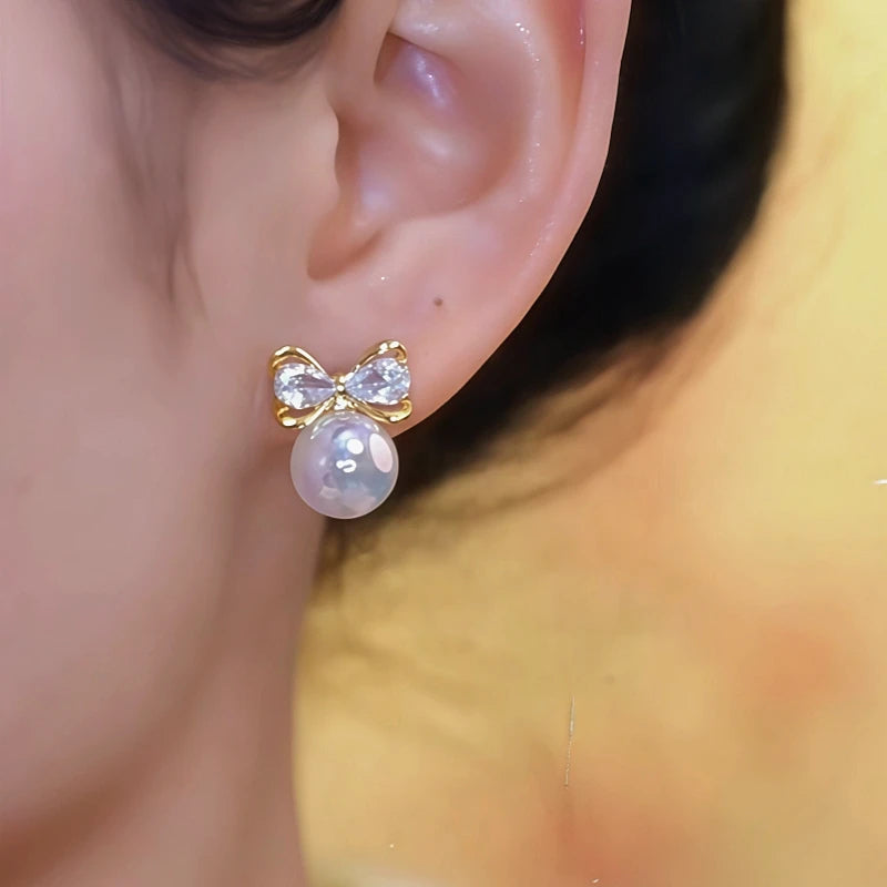 Model showcasing the dangle and style of the 14K Gold-Plated Elegant Zircon Mermaid Bow Pearl Earrings