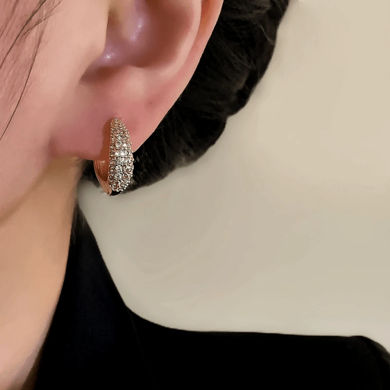 Close-up detail of the sparkling zircons and plating on the gold hoop earrings