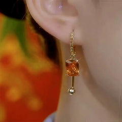 Model showcasing the dangle and style of the 14K Gold-Plated Elegant Zircon Orange Diamond Earrings
