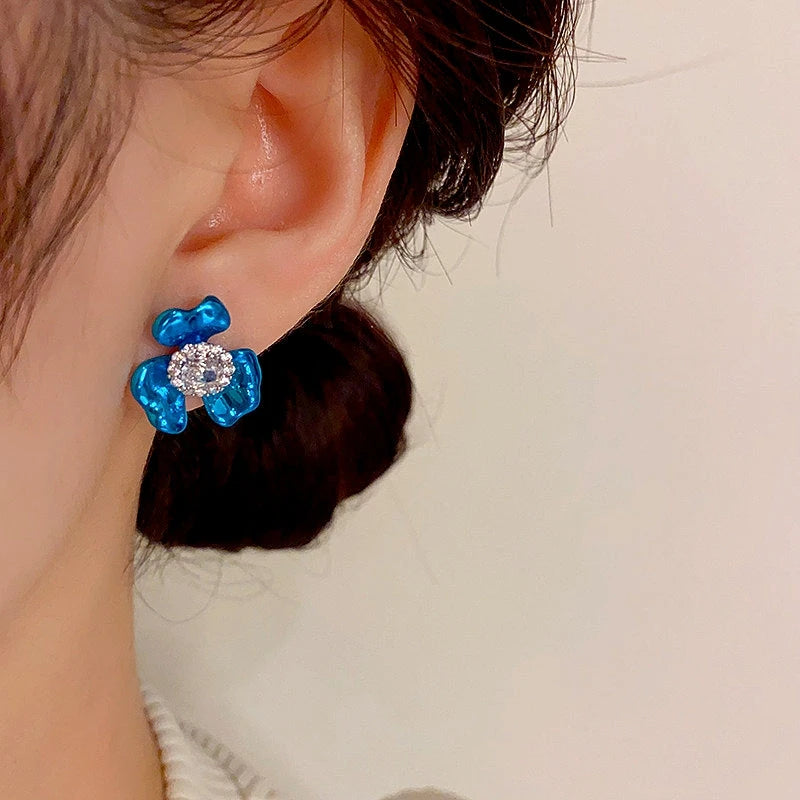 Model showcasing the dangle and style of the 14K Gold-Plated Elegant Zircon Painted Flower Stud Earrings