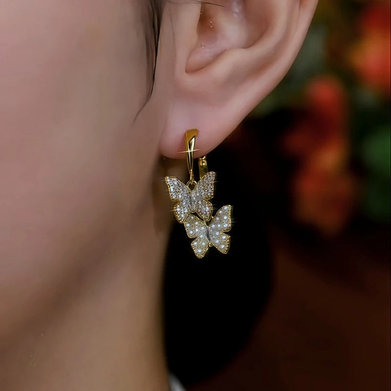 Model showcasing the dangle and style of the 14K Gold-Plated Elegant Zircon Pearl Butterfly Cross Earrings