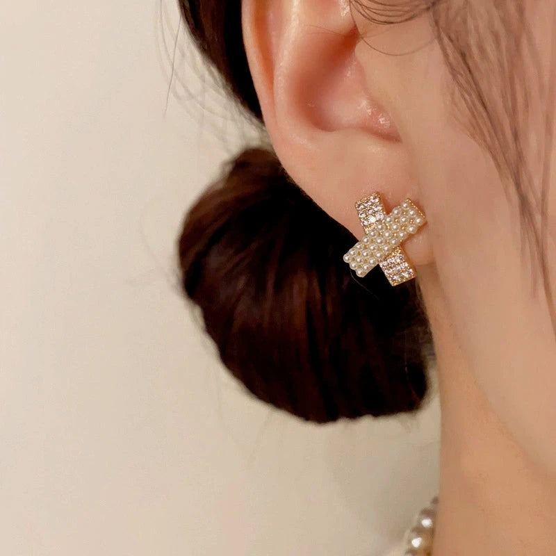Model showcasing the dangle and style of the 14K Gold-Plated Elegant Zircon Pearl Cross Stud Earrings