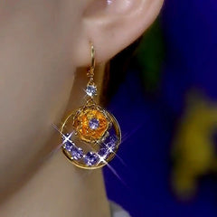 Model showcasing the dangle and style of the 14K Gold-Plated Elegant Zircon Purple Diamond Flower Earrings