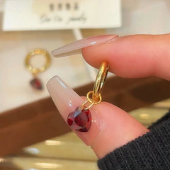 Model showcasing the dangle and style of the 14K Gold-Plated Elegant Zircon Red Heart Earrings