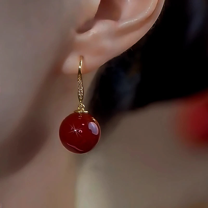 Model showcasing the dangle and style of the 14K Gold-Plated Elegant Zircon Red Pearl Ear Hooks
