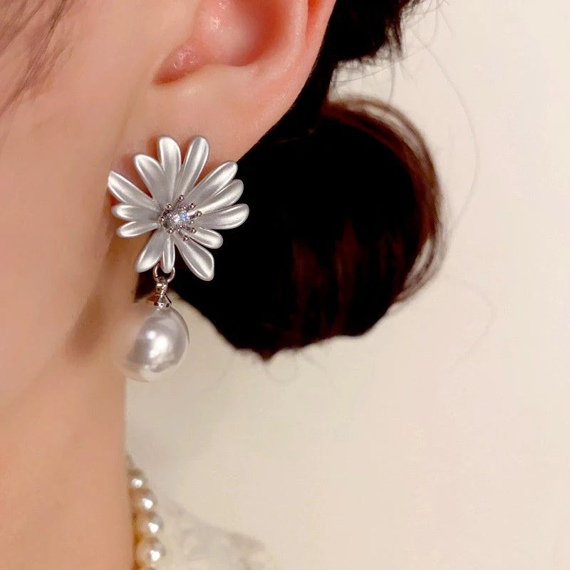 Model showcasing the dangle and style of the 14K Gold-Plated Elegant Zircon Sunflower Pearl Earrings