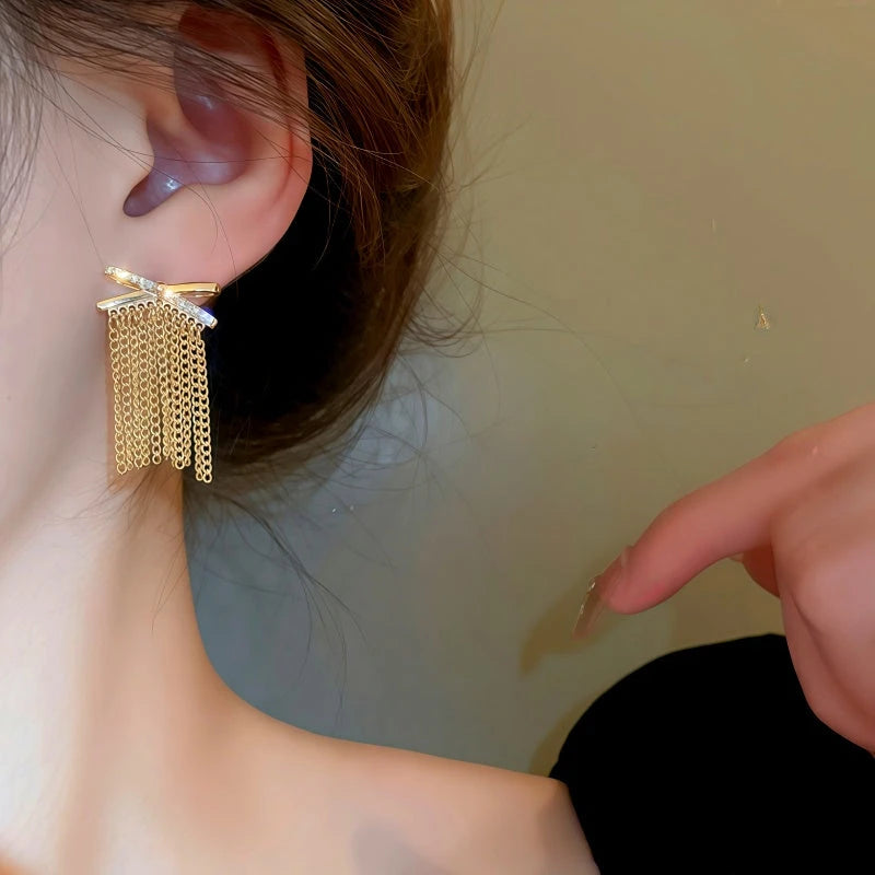 Model showcasing the dangle and style of the 14K Gold-Plated Elegant Zircon X Tassel Earrings