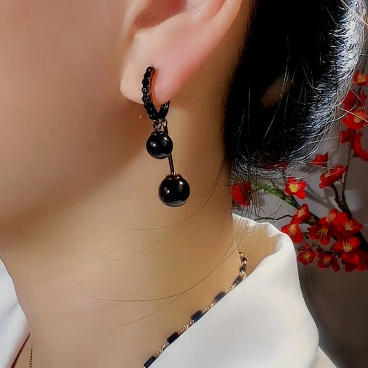 Model showcasing the dangle and style of the 14K Gold-Plated Exquisite Black Ball Pearl Earrings