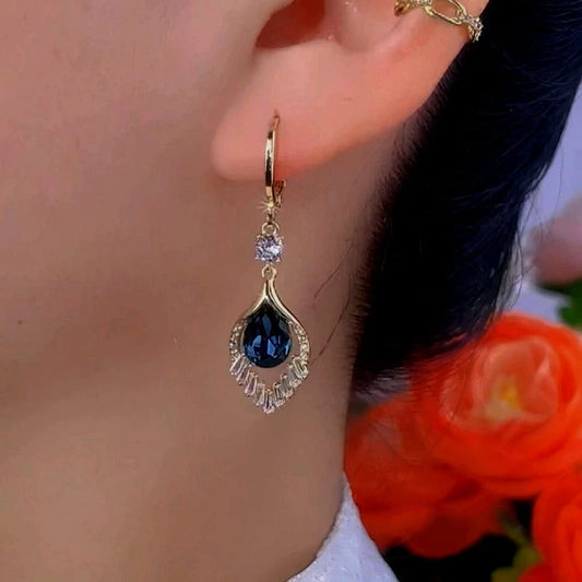 Model showcasing the dangle and style of the 14K Gold-Plated Exquisite Blue Peacock Tail Earrings