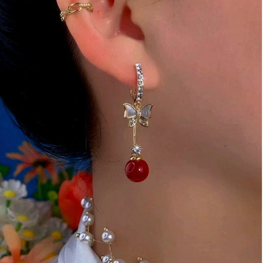 Model showcasing the dangle and style of the 14K Gold-Plated Exquisite Butterfly Red Bead Earrings