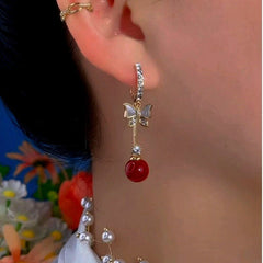Model showcasing the dangle and style of the 14K Gold-Plated Exquisite Butterfly Red Bead Earrings