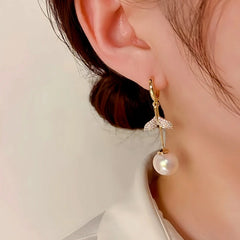 Model showcasing the dangle and style of the 14K Gold-Plated Exquisite Diamond-Filled Fishtail Pearl Tassel Earrings