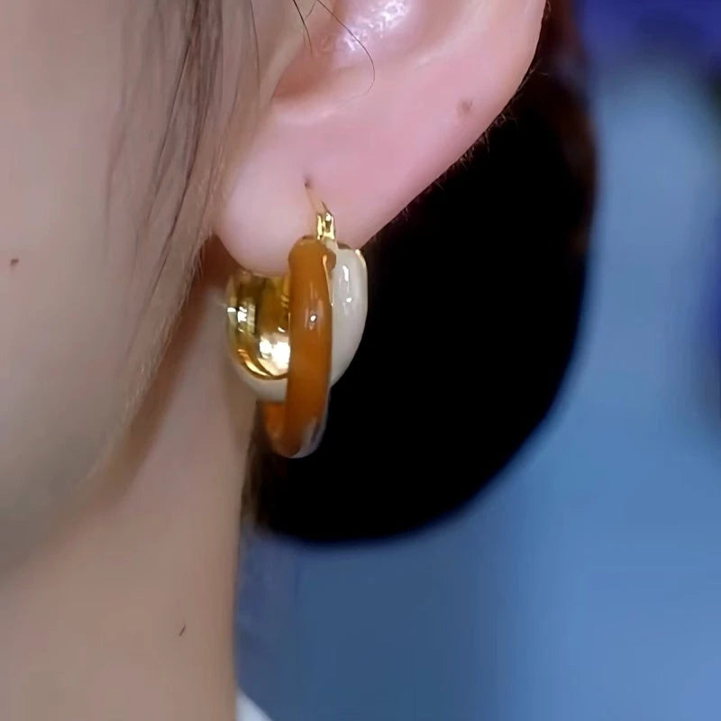 Model showcasing the dangle and style of the 14K Gold-Plated Exquisite Maillard Contrast Color Winding Earrings