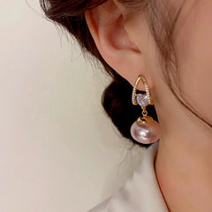 Model showcasing the dangle and style of the 14K Gold-Plated Exquisite Pearl Zircon Heart Earrings