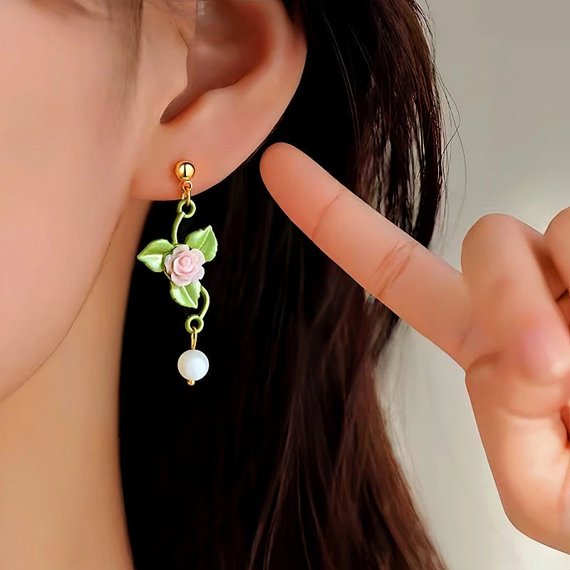 Model showcasing the dangle and style of the 14K Gold-Plated Flower And Green Leaf Earrings