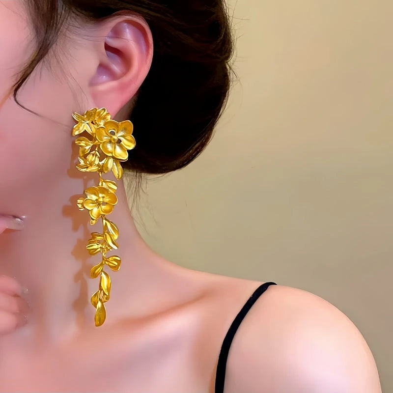 Model showcasing the dangle and style of the 14K Gold-Plated Flower And Leaf Tassel Earrings