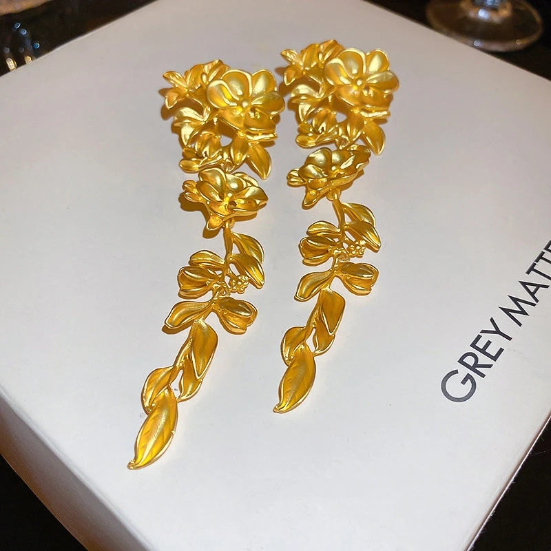 Angled view of the 14K Gold-Plated Flower And Leaf Tassel Earrings