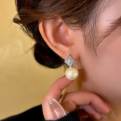 Close-up of rhombus cubic zirconia pearl dangle earring on woman's ear