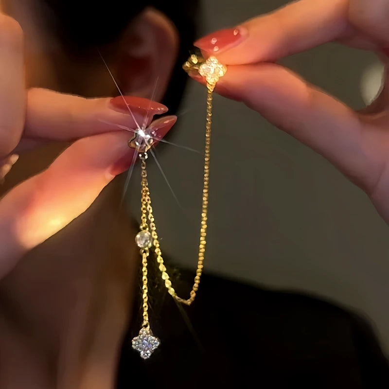 Model showcasing the dangle and style of the 14K Gold-Plated Four-Leaf Clover Tassel Ear Clip Earrings