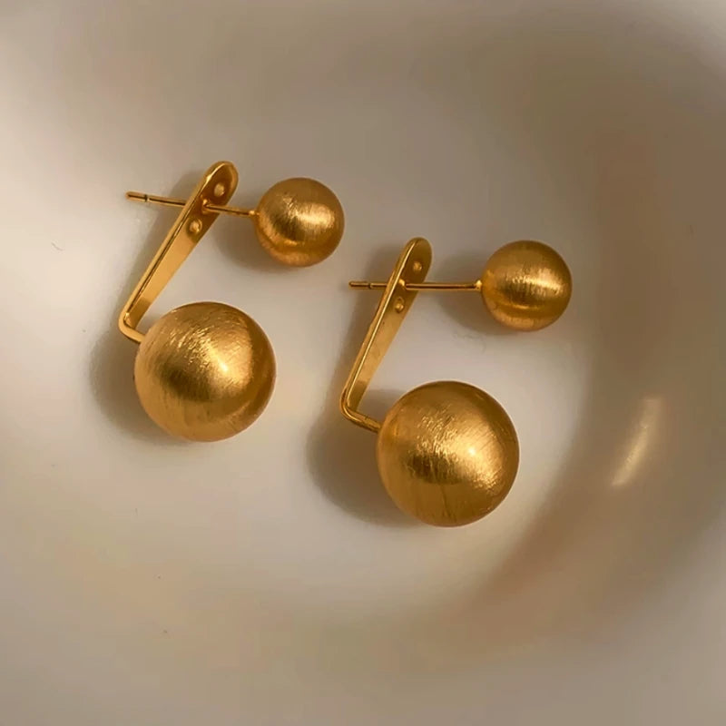 Angled view of the 14K Gold-Plated Frosted Brushed Front And Back Ball Earrings