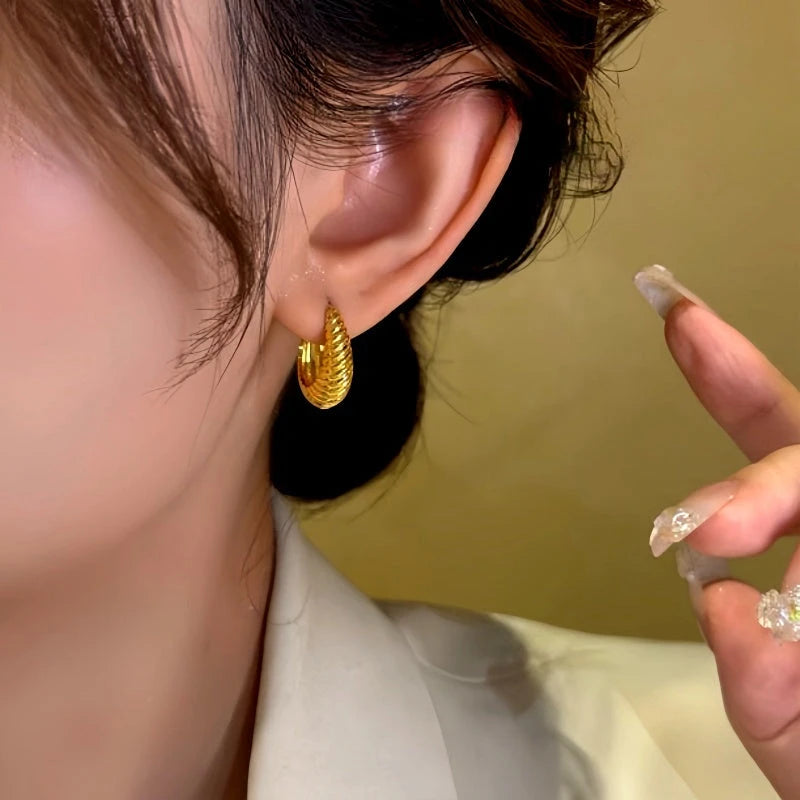 Model showcasing the dangle and style of the 14K Gold-Plated Geometric Elliptical Twist Texture Earrings