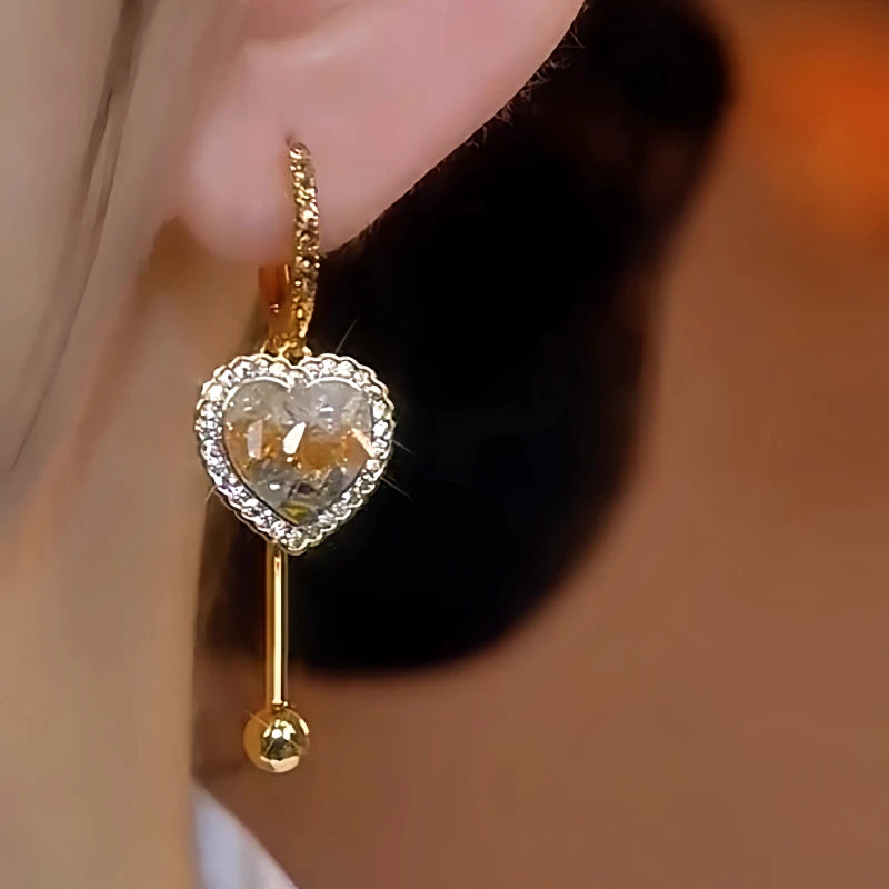 Model showcasing the dangle and style of the 14K Gold-Plated Gradient Crystal Heart Earrings