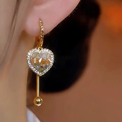 Model showcasing the dangle and style of the 14K Gold-Plated Gradient Crystal Heart Earrings