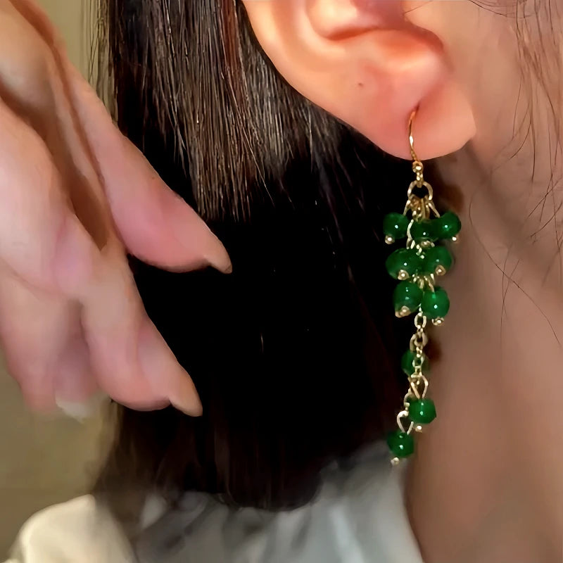 Model showcasing the dangle and style of the 14K Gold-Plated Grape Glass Bead Tassel Ear Hook Earrings