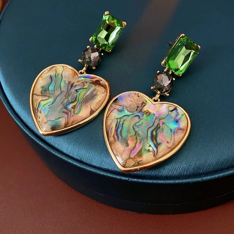 Model showcasing the dangle and style of the 14K Gold-Plated Green Diamond Heart Earrings