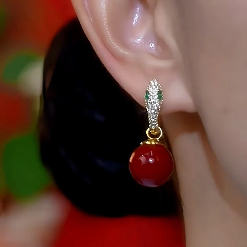 Model showcasing the dangle and style of the 14K Gold-Plated Green Eye Snake-Shaped Pearl Earrings